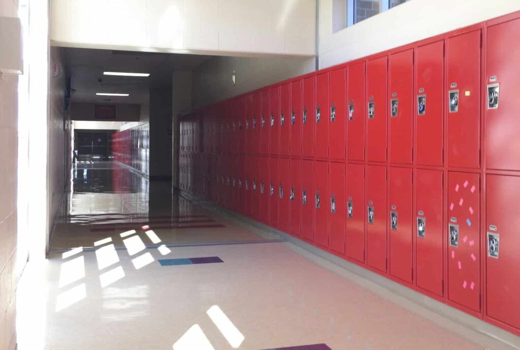 empty high school hall hallway with a row of bright red student lockers , vertical oriented